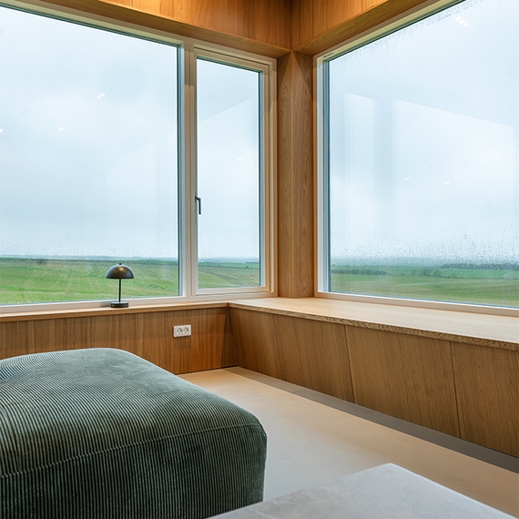 Vinduesniche i sommerhus med UniPanel® og trædetaljer omkring store vinduer.